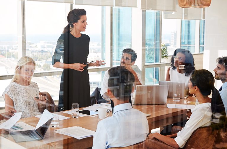 female leader seen through glass in a boardroom meeting
