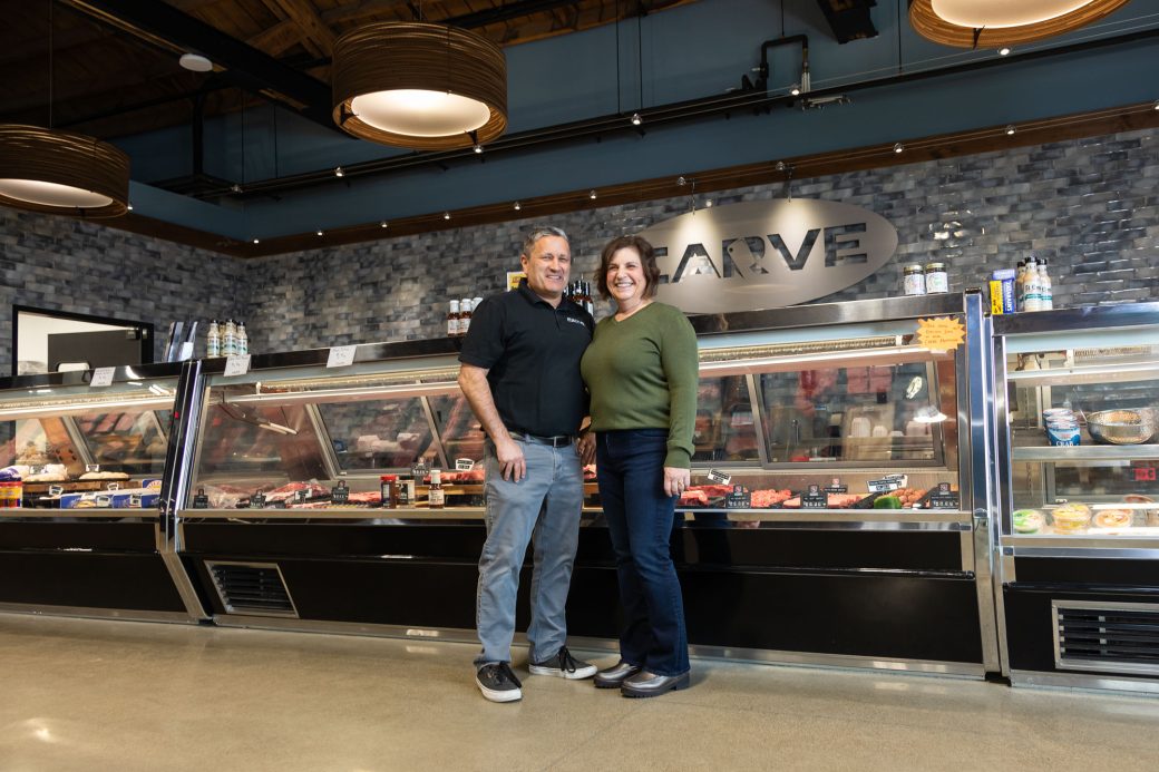 jeff and laurie kaiser smiling in front of carve market meat counter